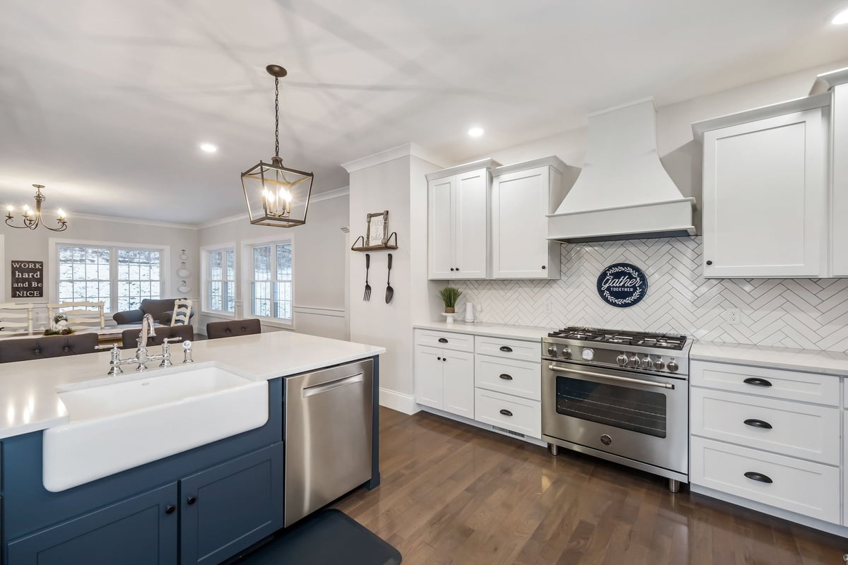 A contemporary kitchen with white cabinetry and island sink