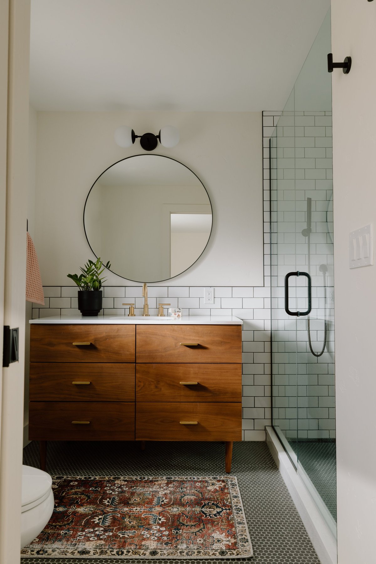 Modern bathroom with wood vanity, round mirror, and glass shower in Boise, Idaho, United States
